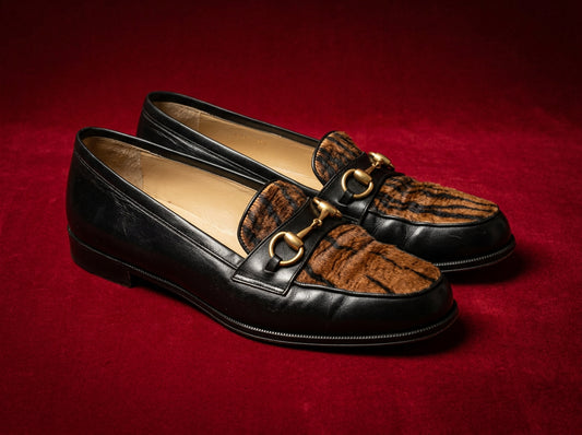 Gucci horsebit loafers with tiger calf-hair on red editorial backdrop, three-quarter view
